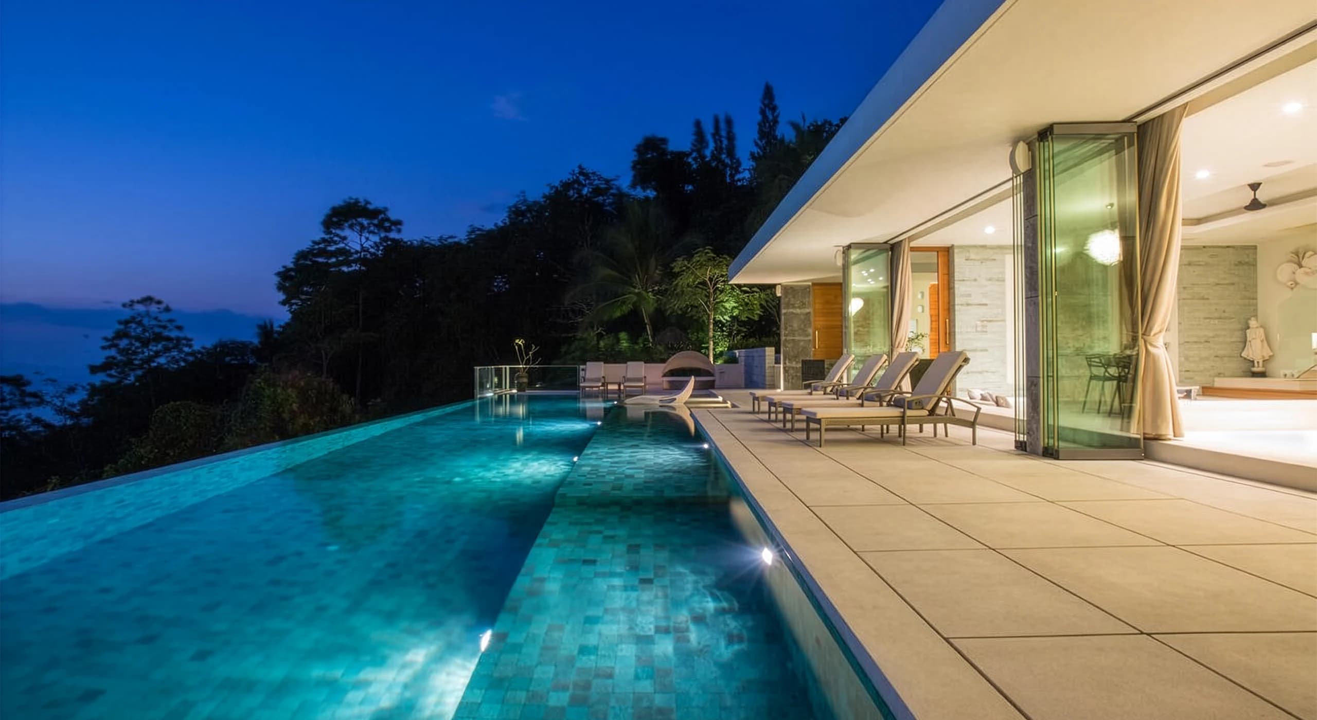 Residência contemporânea com piscina integrada à natureza ao entardecer